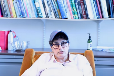 Nergis Mavalvala sits at her desk with bookshelves in the background